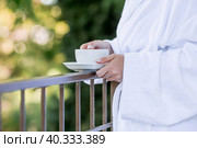 A cup of hot tea in the hands of a girl in a white coat. Morning of the bride. The concept of staying at the hotel and starting the wedding day. Стоковое фото, фотограф Photojuli / Фотобанк Лори