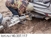 A man checking the hitch mechanism on a car trailer in bad weather. Стоковое фото, фотограф Коханова Наталья / Фотобанк Лори