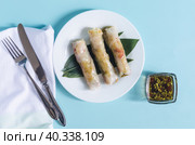 Спринг-роллы из морепродуктов, темный соус и столовые приборы крупным планом на голубом фоне вид сверху. Стоковое фото, фотограф Лозовая Людмила / Фотобанк Лори