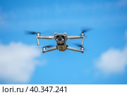 дрон с цифровой камерой высокого разрешения летит на фоне голубого неба с облаками, беспилотник завис в воздухе на фоне неба, коптер парит в воздухе. Стоковое фото, фотограф Руслан Лесков / Фотобанк Лори