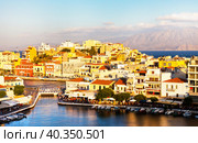 Greece. Crete island. Top view of Agios Nikolaos resort mediterranean town and Voulismeni lake promenade in sunset light. Scenic cityscape. Summer travel and seaside recreation concept (2014 год). Стоковое фото, фотограф Виктория Катьянова / Фотобанк Лори