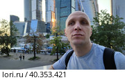 Молодой человек восхищается архитектурой современного города. Мужчина наблюдает за тем, что происходит вокруг. Стеклянные здания и набережная реки на заднем плане. Смотровая площадка возле небоскребов. A young man admires the architecture of a modern city. The man is watching what is happening around. Glass buildings and the river embankment in the background. Observation deck near skyscrapers. Стоковое видео, видеограф Ирина / Фотобанк Лори