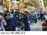 Nizhny Novgorod, Russia - November 21, 2020: GAZ car production plant. People work on assembling line. Young woman in focus only. Редакционное фото, фотограф Alexey Rezvykh / Фотобанк Лори