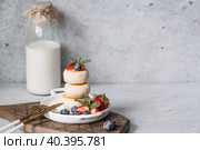 Cottage cheese pancakes, Russian cheesecakes with fresh blueberries, strawberries and mint on a stylish wooden board on a gray concrete table. Natural products. Healthy and delicious breakfast. Стоковое фото, фотограф Photojuli / Фотобанк Лори