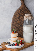 Cottage cheese pancakes, Russian cheesecakes with fresh blueberries, strawberries and mint on a stylish wooden board on a gray concrete table. Natural products. Healthy and delicious breakfast. Стоковое фото, фотограф Photojuli / Фотобанк Лори