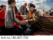 Мальчики поздравляют с Днем Победы 9 мая ветерана Великой Отечественной войны Моргунова Геннадия Михайловича (1923 г.р.) в Парке Победы в 78-ю годовщину Победы, в городе Москве, Россия (2023 год). Редакционное фото, фотограф Николай Винокуров / Фотобанк Лори