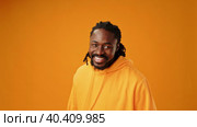 Young african guy in yellow hoodie laughing against yellow background. Стоковое видео, видеограф Сергей Толмачёв / Фотобанк Лори