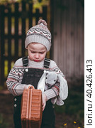 A little boy of 4 years old outdoors with a suitcase and a stuffed rabbit goes on a journey. A beautiful portrait of a child playing on the street. Стоковое фото, фотограф Photojuli / Фотобанк Лори