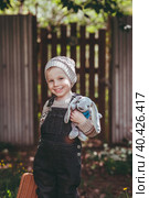 A little boy of 4 years old outdoors with a suitcase and a stuffed rabbit goes on a journey. A beautiful portrait of a child playing on the street. Стоковое фото, фотограф Photojuli / Фотобанк Лори