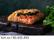 Pie with trout and spinach filling in puff pastry served on dark wooden board. Стоковое фото, фотограф Оксана Чаюн / Фотобанк Лори