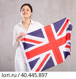 Reliant young woman holds big national British flag with confident smile showing teeth. Стоковое фото, фотограф Яков Филимонов / Фотобанк Лори