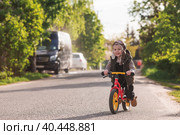 A cheerful little boy rides a bicycle outdoors. A happy child walks in the spring park. The baby is dressed in a fashionable vest, overalls. An aviator's hat is on his head. Стоковое фото, фотограф Photojuli / Фотобанк Лори