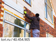 A man works with a drill, attaches thermal panels made of clinker. Стоковое фото, фотограф Юрий Поздников / Фотобанк Лори