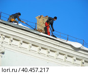 Рабочий коммунальной службы очищает крышу жилого дома от скопившегося снега. Никольская улица, 5/1, строение 1. Тверской район. Город Москва (2014 год). Редакционное фото, фотограф lana1501 / Фотобанк Лори