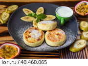 Syrniki or cheese pancakes with cream sauce and bananas on a plate on wooden table close up. Стоковое фото, фотограф Татьяна Терехина / Фотобанк Лори