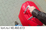 A man rolls a large red suitcase on the sidewalk on wheels. View from above. Стоковое видео, видеограф Юрий Поздников / Фотобанк Лори