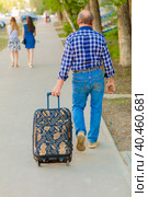 A man drags a suitcase on wheels along the sidewalk in the city. Стоковое фото, фотограф Юрий Поздников / Фотобанк Лори