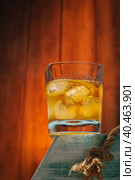 A glass of whiskey with ice on a stand. Wooden background. Alcoholic drink. Moscow Russia March 27, 2022. Стоковое фото, фотограф Юрий Поздников / Фотобанк Лори