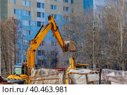 An excavator with a large bucket digs a hole in the yard. Стоковое фото, фотограф Юрий Поздников / Фотобанк Лори