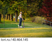Mom rides a scooter with children in the park in summer. Russia Moscow September 24, 2020. Редакционное фото, фотограф Юрий Поздников / Фотобанк Лори