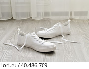 White sneakers with untied laces are on floor. Стоковое фото, фотограф Володина Ольга / Фотобанк Лори