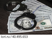One hundred dollar bills and steel handcuffs close up. Стоковое фото, фотограф Артем Курутин / Фотобанк Лори