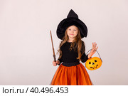 Halloween Party girl. Funny child girl in witch costume on Halloween pumpkin pot and magic wand on white background. Стоковое фото, фотограф Ирина Михайличенко / Фотобанк Лори