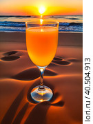 A glass of orange juice on the sea sand, small waves, romantic sunset. Стоковое AI-изображение, AI-художник Сергей Елизарьев / Фотобанк Лори