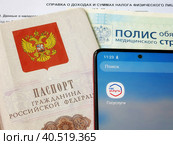 Персональные данные гражданина РФ: паспорт, медицинский полис, и телефон с электронным приложением Государственные слуги (2023 год). Редакционное фото, фотограф Татьяна Т / Фотобанк Лори