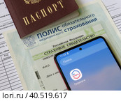 Персональные данные гражданина РФ: паспорт, медицинский полис, СНИЛС и телефон с электронным приложением Государственные слуги (2023 год). Редакционное фото, фотограф Татьяна Т / Фотобанк Лори