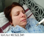 Sick woman in bed. Headache, runny nose and cold. Paleness of the face and faintness of the body. Feeling unwell. The patient lies on a pillow, holds a thermometer and measures the temperature. Стоковое фото, фотограф Юлия Петровская / Фотобанк Лори
