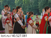 Russian folk traditions. Folk festivals. Children in beautiful Russian traditional outfits sing songs, dance and lead a round dance in Tsaritsyno Park. National Russian clothes. Sundresses and kokoshniks. (2023 год). Редакционное фото, фотограф Photojuli / Фотобанк Лори