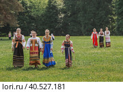 Russian folk traditions. Folk festivals. Children in beautiful Russian traditional outfits sing songs, dance and lead a round dance in Tsaritsyno Park. National Russian clothes. Sundresses and kokoshniks. (2023 год). Редакционное фото, фотограф Photojuli / Фотобанк Лори