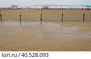 Vityazevo Russia, August 10 2021 A puddle on a sandy quartz medicinal beach after heavy rain. Consequences of bad weather and typhoon. The edge of the beach holiday season. Tourists in the background. Редакционное фото, фотограф Юлия Петровская / Фотобанк Лори
