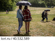 Люди гуляют под зонтом в парке в дождливую погоду в городе Москве, Россия (2023 год). Редакционное фото, фотограф Николай Винокуров / Фотобанк Лори