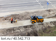 ANGARSK, IRKUTSK REGION, RUSSIA - May 24, 2023: Road workers compacting gravel with vibratory rammer and mini roller on footpath under construction. Road construction seasonal works. Top view. Редакционное фото, фотограф Виктория Катьянова / Фотобанк Лори