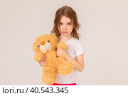 Offended little girl holding a teddy bear and crying on a white background. Стоковое фото, фотограф Ирина Михайличенко / Фотобанк Лори