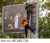Монтажники клеят рекламный плакат на щит-призматрон (2023 год). Редакционное фото, фотограф Вячеслав Палес / Фотобанк Лори