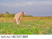 A Muslim senior man wearing an embroidered skullcap and white traditional clothes prays. Стоковое фото, фотограф Ирина Кононова / Фотобанк Лори