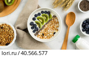 Zoom in healthy breakfast consisting of natural yogurt with granola, kiwi fruit, chia seeds and blueberries, top view. Concept of healthy food, vegetarian eating. Стоковое видео, видеограф Мария Зубарева / Фотобанк Лори