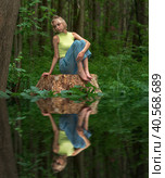 Teenage girl sits on a stump in a natural forest park with a sad and thoughtful look, reflected in the water. Стоковое фото, фотограф Евгений Харитонов / Фотобанк Лори