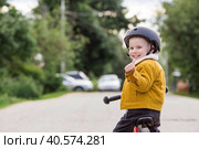 A cheerful little boy rides a running bike in a helmet outdoors. A happy child is engaged in an active sport. Protection. Life insurance and child safety. Стоковое фото, фотограф Photojuli / Фотобанк Лори
