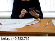 Девушка держит телефон и ручку над столом с бумагами. A woman is holding a pen and a smart phone in her hand. Стоковое фото, фотограф Iva Noel / Фотобанк Лори
