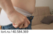 A pot-bellied man is trying to pull denim pants on an obese waist in a close-up room, the side view is unrecognizable. The concept of malnutrition and overeating. Стоковое видео, видеограф Денис Кебедов / Фотобанк Лори
