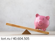 Керамическая копилка розового цвета на деревянных качелях или весах на абстрактном фоне, бизнес-концепция, шаблон для дизайнера. Стоковое фото, фотограф Сергей Чайко / Фотобанк Лори
