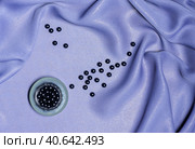 Scattering of black nacreous beads on silk purple draped fabric. Стоковое фото, фотограф Галина  Василенко / Фотобанк Лори