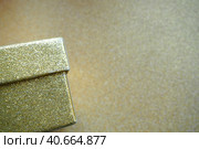 Golden gift box on a golden background. Decorative surprise box. Copy space. Стоковое фото, фотограф Юлия Петровская / Фотобанк Лори