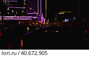 Nighttime car traffic in a major city. Beautiful backlighting of the city from a hotel. Light defocus. Night city life. Стоковое видео, видеограф Воловодов Владимир / Фотобанк Лори