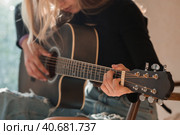 Music and hobbies. A talented young musician girl sits alone and composes songs on the guitar. The girl plays a calm melody on a musical instrument. Стоковое фото, фотограф Photojuli / Фотобанк Лори