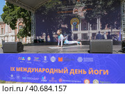 Международный день йоги в парке Царицыно. Инструктор на сцене показывает асану. (2023 год). Редакционное фото, фотограф Сергей Никифоров-Гордеев / Фотобанк Лори